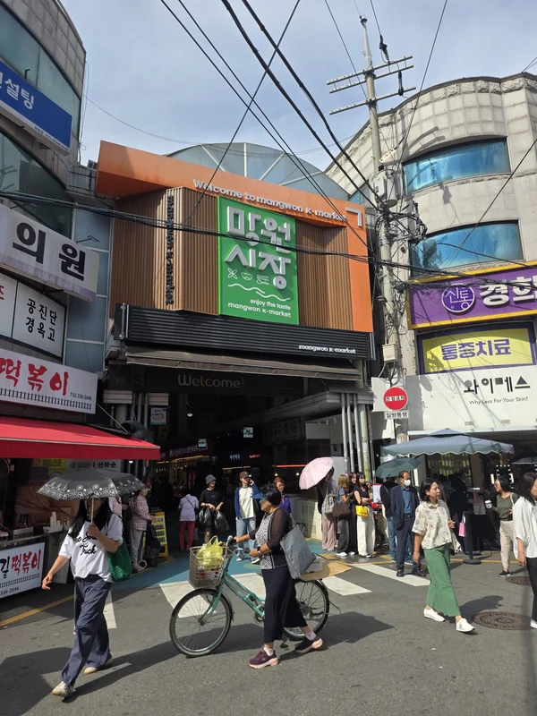 망원시장 입구의 초록색 간판과 지나가는 사람들
